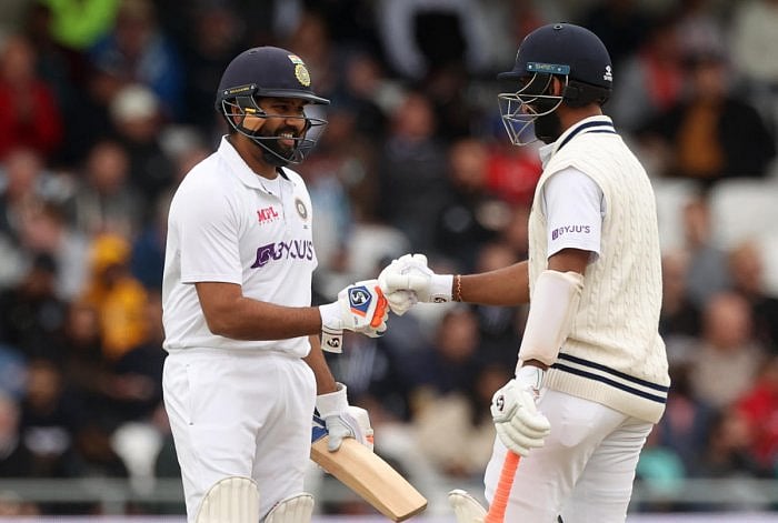 Rohit Sharma celebrates his half century with Cheteshwar Pujara. Credit: Reuters Photo