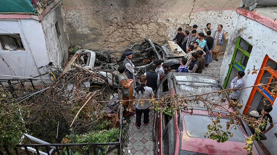 Afghan residents and family members of the victims gather next to a damaged vehicle inside a house, day after a US drone airstrike in Kabul on August 30, 2021. Credit: AFP Photo