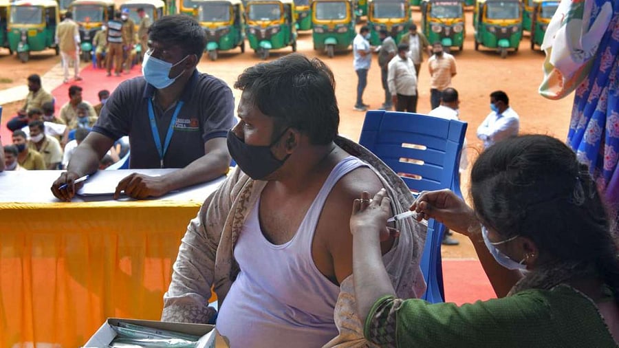 An auto-rickshaw driver receives a jab of Covid-19 vaccine during a free vaccination drive for the drivers in Bangalore. Credit: DH Photo