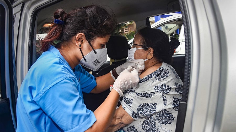 A beneficiary receives a dose of Covid-19 vaccine inside a car at a hotel in Patna. Credit: PTI File Photo