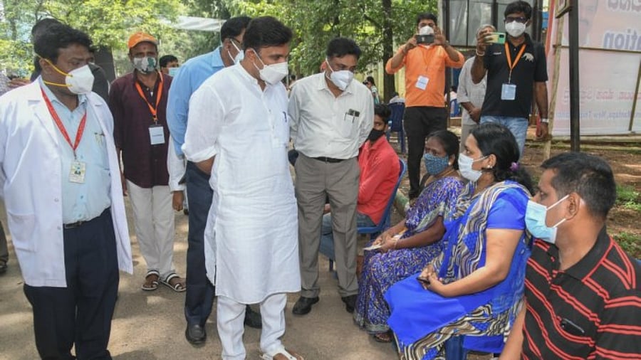Health and Family Welfare Minister Dr K Sudhakar, interacts with people waiting for Covid vaccination, in Bengaluru on Wednesday. Credit: DH Photo/S K Dinesh
