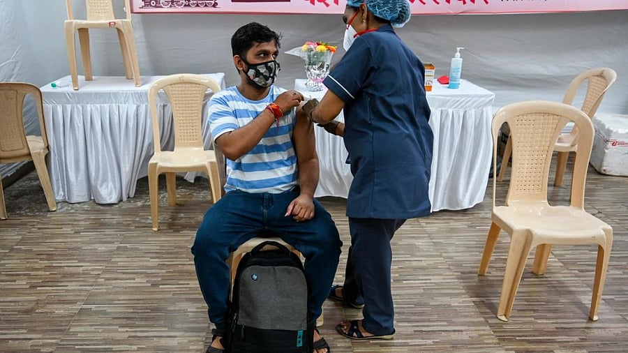 A health worker inoculates a man with a dose of the Covishield vaccine against the Covid-19 coronavirus, at a temporary vaccination centre set up inside a school in Mumbai. Credit: AFP Photo