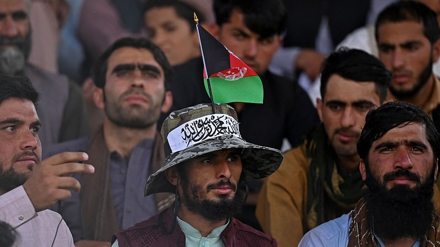 spectator wearing a hat with an Afghanistan flag and Taliban ribbon watches the Twenty20 cricket trial match being played between two Afghan teams 'Peace Defenders' and 'Peace Heroes' at the Kabul International Cricket Stadium in Kabul on September 3, 2021. Credit: AFP Photo