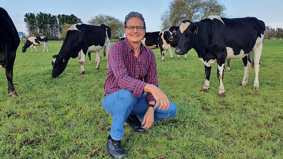 This undated handout photo received on September 13, 2021, from the Research Institute for Farm Animal Biology shows researcher Lindsay Matthews posing next to cows at a farm at an undisclosed location in New Zealand. Credit: Research Institute for Farm Animal Biology/AFP