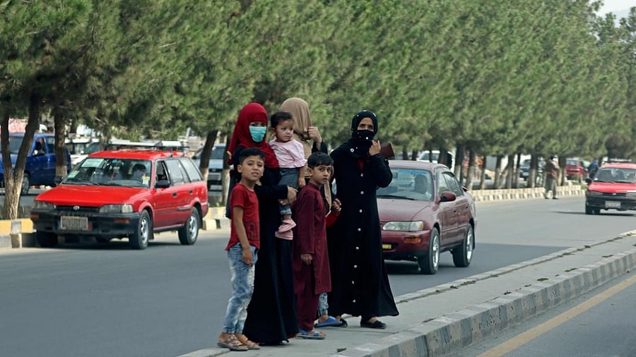 Afghan women along with children stand on a road divider at a street in Kabul. Credit: AFP Photo