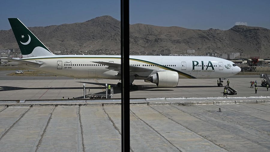 Members of ground staff stand on the tarmac beside a Pakistan International Airlines (PIA) aircraft, the first commercial international flight since the Taliban retook power last month, at the airport in Kabul. Credit: AFP Photo