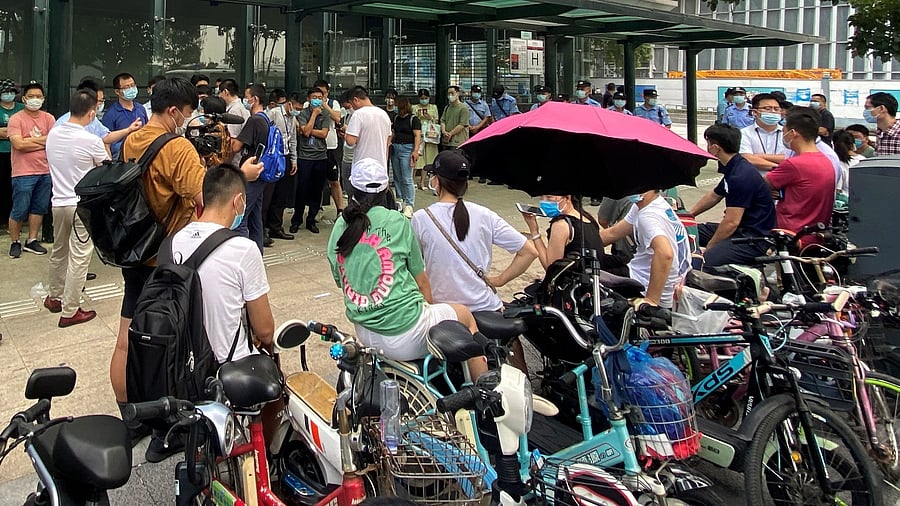 People gather to demand repayment of loans and financial products as security personnel guards outside Evergrande's headquarters in Shenzhen, Guangdong province, China, September 15, 2021. Credit: Reuters Photo