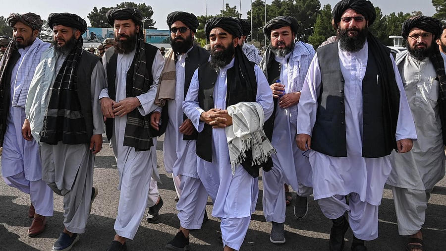 Taliban spokesman Zabihullah Mujahid (C, holding shawl) arrives as he is accompanied by officials to address a media conference. Credit: AFP File Photo