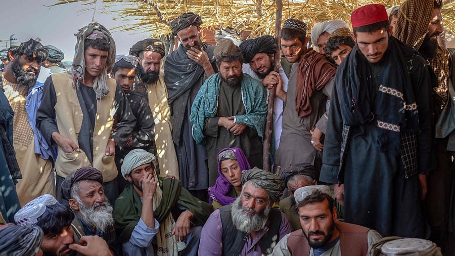 Men gather around bags containing heroin and hashish as they negotiate and check quality at a drug market in Kandahar. Credit: AFP Photo