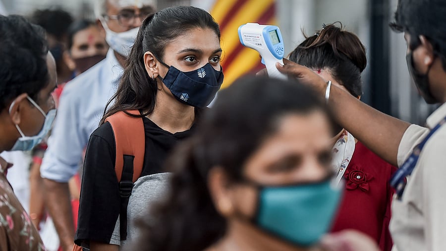 A health worker checks body temperature of a traveler as a precaution against the coronavirus before allowing her to proceed at a railway station in Mumbai. Credit: PTI Photo