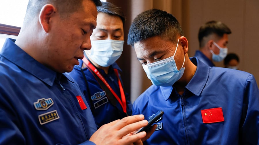 Staff members of the Jiuquan Satellite Launch Center look at a phone during a news conference ahead of the launch of the Long March-2F Y13 rocket, carrying the Shenzhou-13 spacecraft and three astronauts in China's second crewed mission to build its own space station, at Jiuquan Satellite Launch Center near Jiuquan, Gansu province, China, October 14, 2021. Credit: Reuters Photo