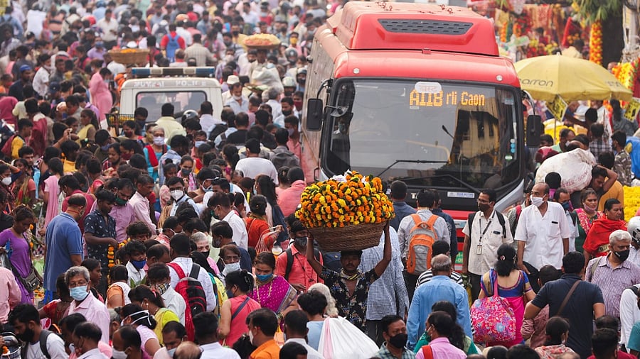 A man carrying flower garlands walks through a crowded market ahead of the religious festival of Dussehra. Credit: Reuters Photo