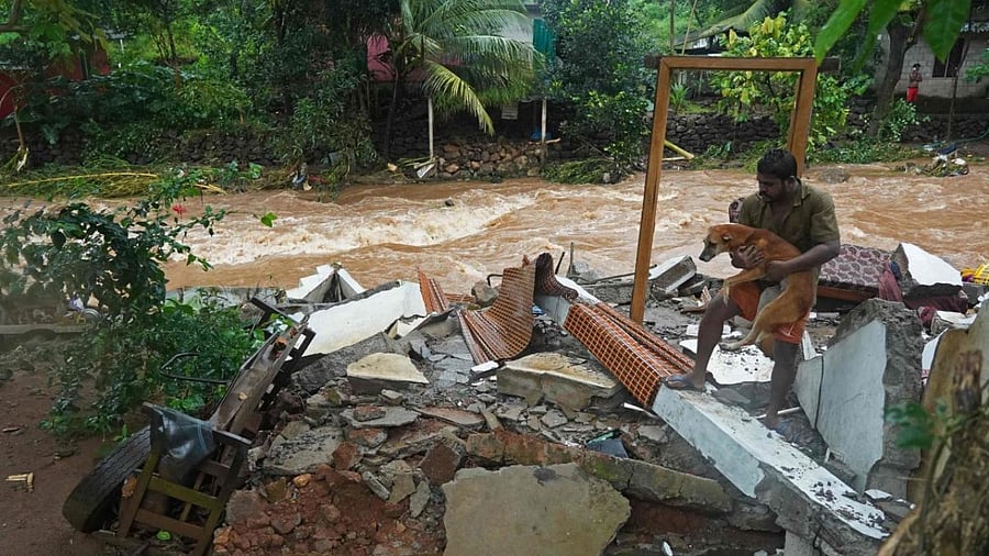 A resident carries a dog amid debris of his damaged house after flash floods caused by heavy rains at Thodupuzha in India's Kerala state. Credit: AFP Photo