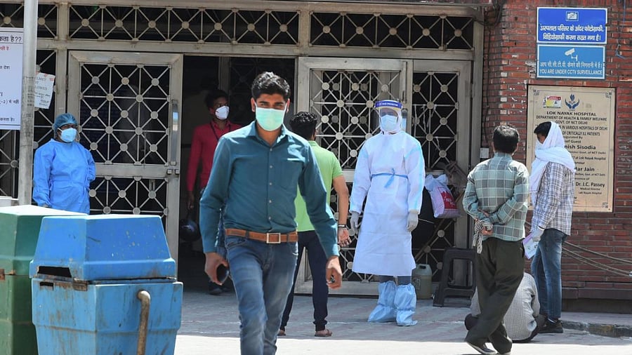 A medic wearing a protective suit as a preventive measure against coronavirus, stands outside the building gate of Lok Nayak Jai Prakash Narayan (LNJP) hospital, in New Delhi. Credit: PTI File Photo