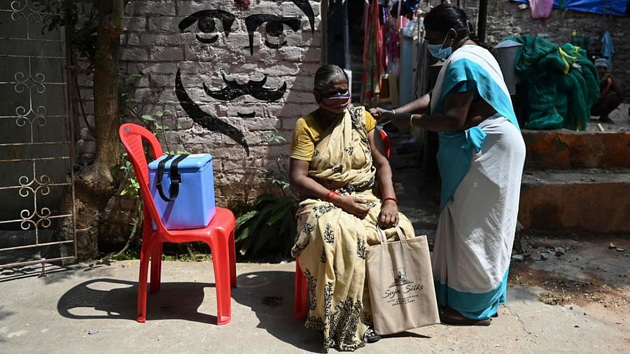 A woman reacts as a health worker inoculates her with a dose of the Covid-19 coronavirus vaccine during a door to door vaccination camp. Credit: AFP Photo