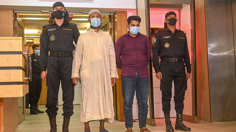 Rapid Action Battalion (RAB) personnel parade Shaikot Mondol (2R) and Robiul Islam (2L), who are accused for allegedly spreading rumours which triggered the recent religious violence against Bangladesh's Hindu minority community. Credit: AFP Photo