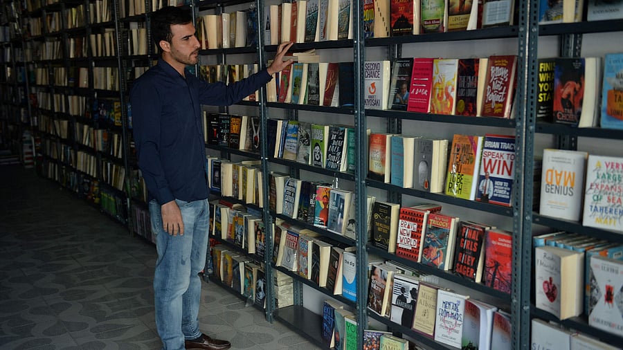 Mustafa Barak, law student and customer of Saadat Books, a store specialized in English-language texts, looking at a book in Kabul. Credit: AFP Photo