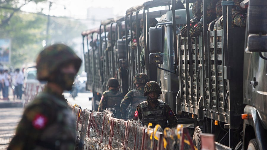 Soldiers stand next to military vehicles as people gather to protest against the military coup, in Yangon, Myanmar. Credit: Reuters Photo