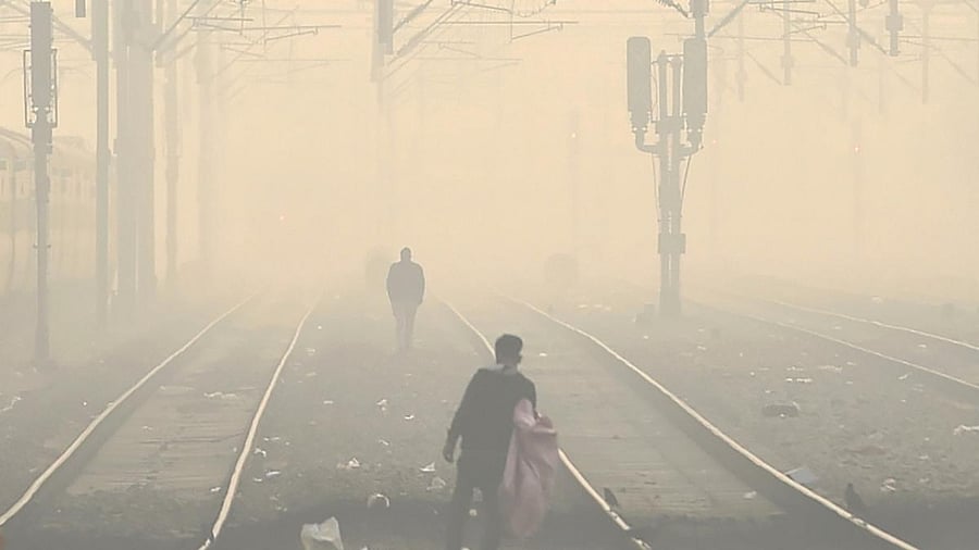 People cross a railway track amid hazy weather conditions at Shivaji Bridge railway station, in New Delhi. Credit: PTI File Photo