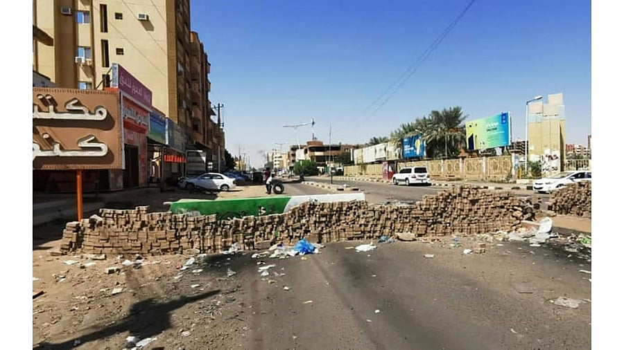 A young Sudanese man rolls a tyre before setting it on fire in front of a street barricades built overnight by anti-coup demonstrators in the capital Khartoum, following calls for civil disobedience to protest last month's military coup. Credit: AFP Photo