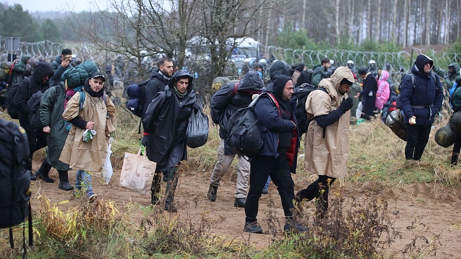Migrants gather near a barbed wire fence in an attempt to cross the border with Poland in the Grodno region, Belarus. Credit: Reuters Photo
