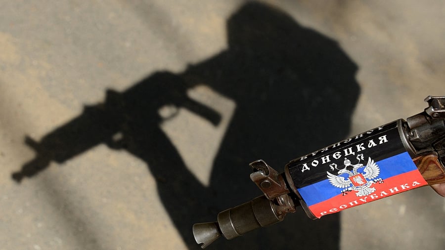 An armed man in military fatigues holds a machine gun colored by a flag of self-named "People's Republic of Donetsk". Credit: AFP File Photo