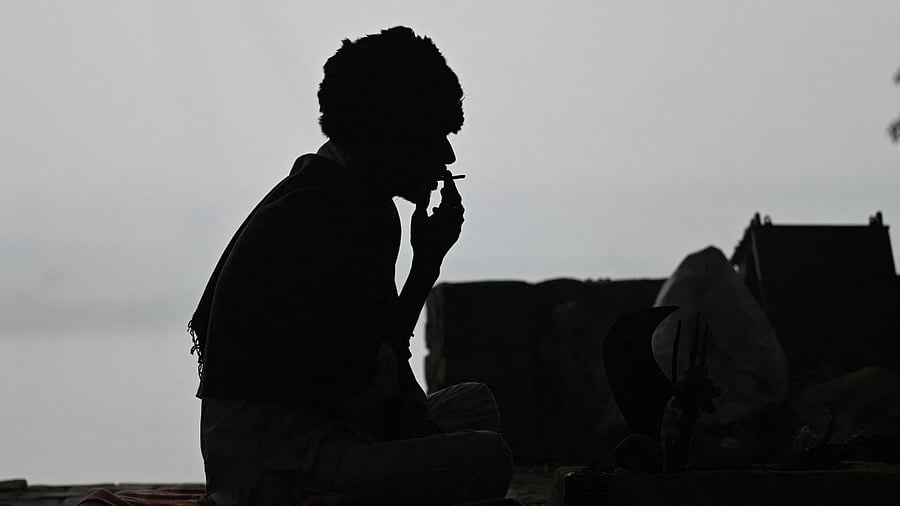 A man is silhouetted as he smokes on the banks of Yamuna river. Credit: AFP Photo