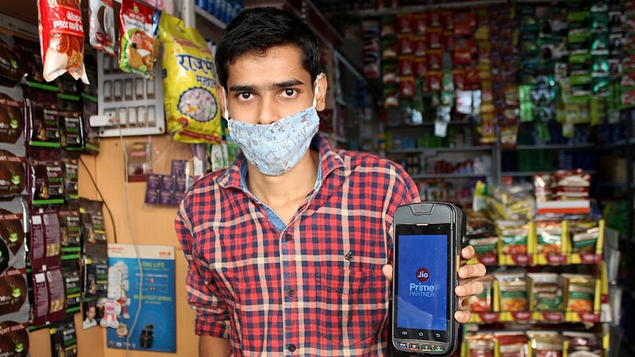A shopkeeper displays the JioMart app, which offers discounts on products. Credit: Reuters