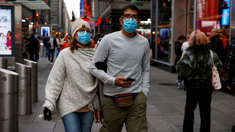 People wearing protective face masks, amid the coronavirus disease (Covid-19) pandemic, walk through Times Square. Credit: Reuters Photo