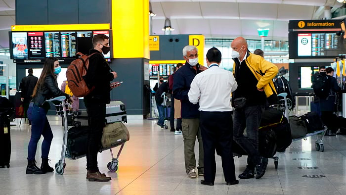 Travellers wearing a face mask or covering due to the Covid-19 pandemic, stand at check-in desks at Terminal 2 of Heathrow Airport in west London. Credit: AFP Photo