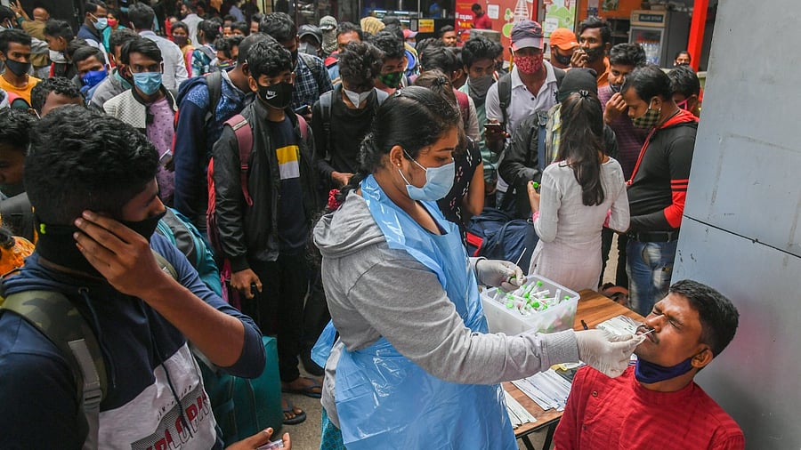 A health worker conducts Covid-19 testing of commuters amid fear of spread of a new variant of Covid-19. Credit: DH File Photo/S K Dinesh
