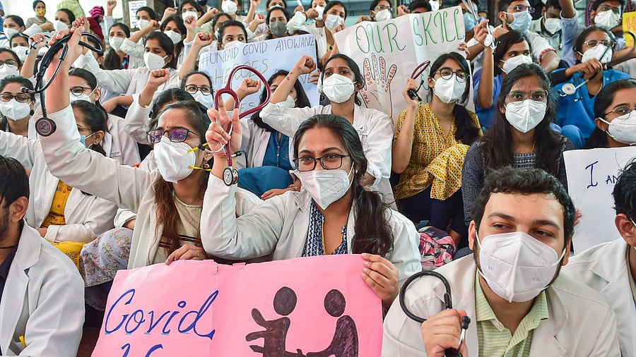 Medical students and resident doctors hold placards and raise slogans during a protest demanding restructuring of the academic fees, payment of Covid-risk allowance and timely payment of stipend to postgraduates and interns, at Victoria Hospital in Bengaluru, Tuesday, November 30, 2021. Credit: PTI Photo