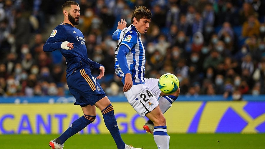 Real Madrid's French forward Karim Benzema (L) challenges Real Sociedad's French defender Robin Le Normand during the Spanish League football match between Real Sociedad and Real Madrid CF at the Anoeta stadium in San Sebastian on December 4, 2021. Credit: AFP Photo