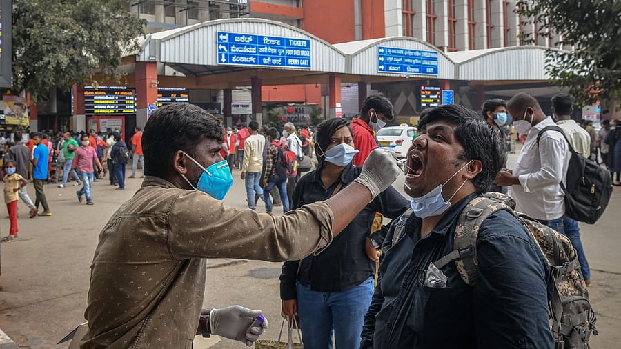 A health official conducts a Covid-19 coronavirus screening of a passenger at a railway station. Credit: AFP Photo