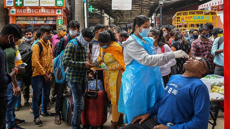 A health official conducts a Covid-19 coronavirus screening of a passenger at a railway station during an enforcement drive in Bangalore on December 3, 2021. Credit: AFP File Photo