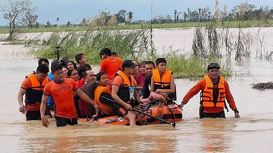 In this photo provided by the Philippine Coast Guard, rescuers pull a rubber boat as they assist residents who were trapped in their homes after floodwaters caused by Typhoon Rai inundated their village in Negros Occidental, central Philippines. Credit: AP/PTI photo
