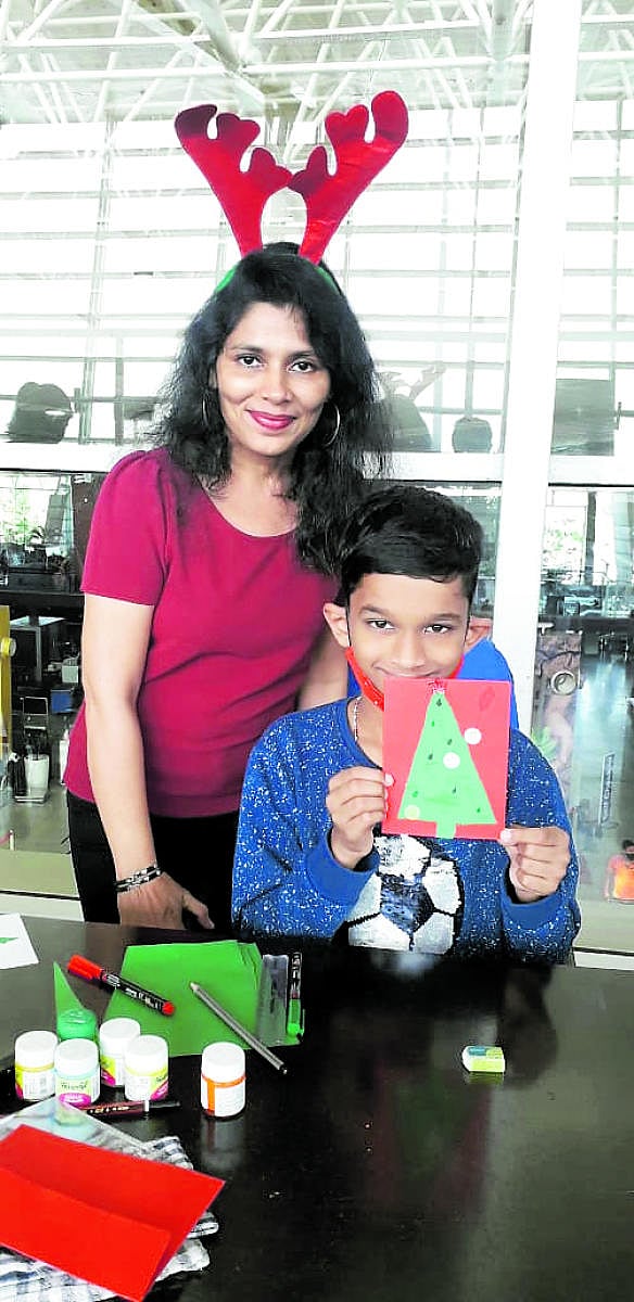 Artist Sapna Noronha and a child participant with a Christmas greeting card made at the Mangaluru International Airport on Tuesday.