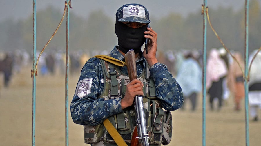 A Taliban fighter speaks on a mobile phone as Afghans arrive at Eidgah to offer special prayers for rains in Kandahar on December 25, 2021. Credit: AFP Photo