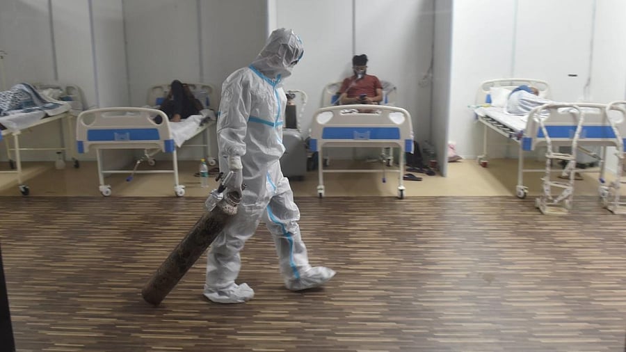 A doctor drags an oxygen cylinder at CWG village Covid-19 Care Centre near Akshardham, in New Delhi. Credit: PTI file photo