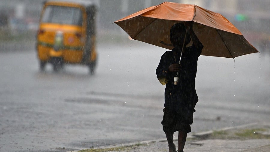 A boy holds an umbrella while walking through a street during a heavy rain shower in Chennai on December 30, 2021. Credit: AFP Photo