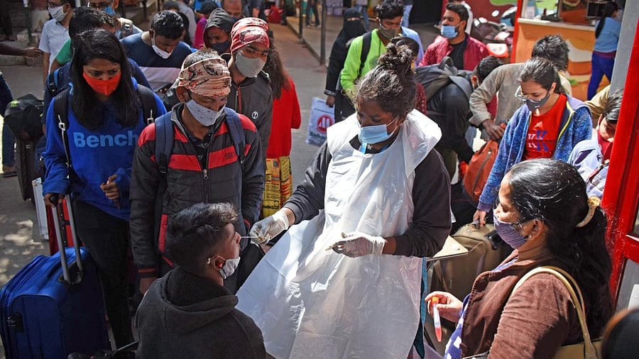 A health care worker collects swab samples from people for coronavirus at city railway station in Bengaluru. Credit: DH Photo