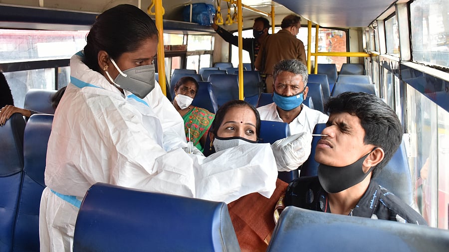 Swab tests to passengers in a bus at the KSRTC bus stand. Credit: DH Photo