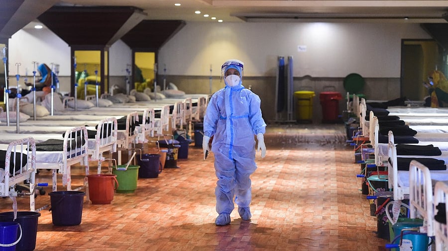 A health worker walks inside the Shehnai Banquet Hall, a Covid-19 care facility, during the third wave of the coronavirus, in New Delhi. Credit: PTI Photo