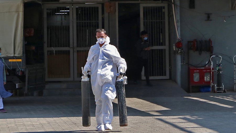 A Health workers carries oxygen cylinder for Covid patients at Civil Hospital in Ahmedabad. Credit: IANS