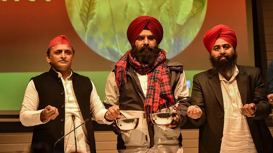 Samajwadi Party President Akhilesh Yadav takes an oath at party office in Lucknow. Farmer leader Tajinder Singh Virk (M) is also seen. Credit: PTI Photo