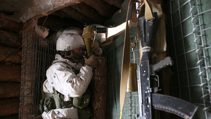 An Ukrainian Military Forces serviceman, watches through spyglass in a dugout on the frontline with Russia-backed separatists near Gorlivka, Donetsk region. Credit: AFP Photo