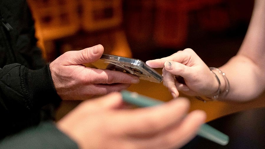 Patrons show proof of their Covid-19 vaccination on their phones while entering Pitcher’s bar in Washington. Credit: AFP Photo