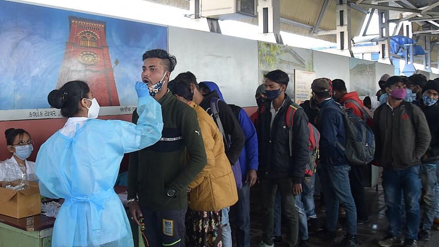 A health worker takes a swab sample from a passenger to test for the Covid-19 coronavirus at Kalupur Railway Station in Ahmedabad on January 25, 2022. Credit: AFP Photo