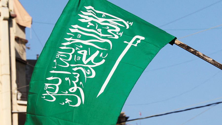 The flag of Saudi Arabia flutters in front of a poster. Credit: Reuters Photo
