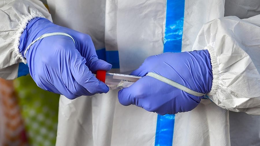 A health worker with swab sample of a commuter for Covid-19 test, amid fear of spread of a new variant of Covid-19, at K R Market in Bengaluru. Credit: PTI Photo